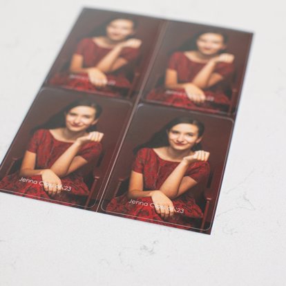 A single sheet of four wallets that are freshly die cut featuring senior portraits of a senior in a red dress