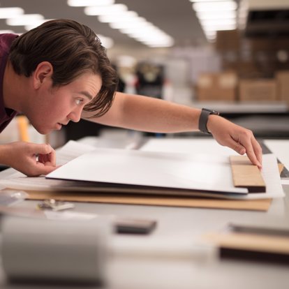 A worker inspects a metal print for accuracy and quality in our lab.