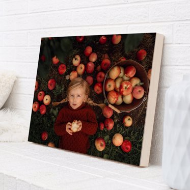 Personalized wood photo print from Mpix of a toddler laying in the grass of an apple field next to a basket of apples