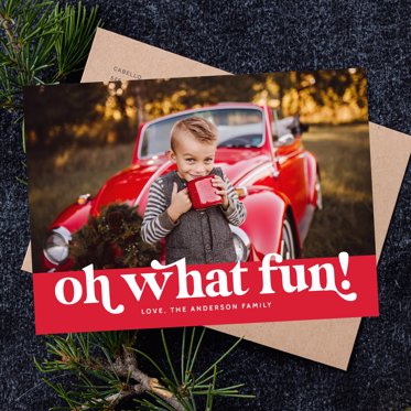 Personalized Christmas Card from Mpix featuring your photo on a red background with "Oh What Fun" written in white block lettering, the card is resting on a kraft paper envelope.