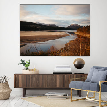 A large framed textile print displayed in an office waiting room featuring a photo of a small lake with the mountains in the distance.