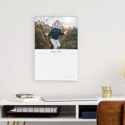 An example of a wall calendar hanging on a wall using the binding on top.