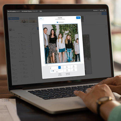 A laptop open to the Mpix website ordering platform. The screen shows a photo being cropped.