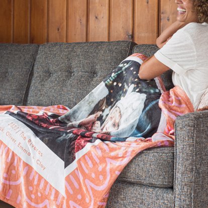 A personalized blanket from Mpix draped on a couch featuring a scallopped and striped design with room for a large personalized photo and custom text. 