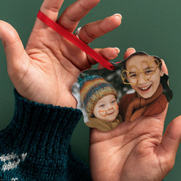 Ornate shaped ornament with a red ribbon for hanging featuring a photo of a brother and sister smiling.