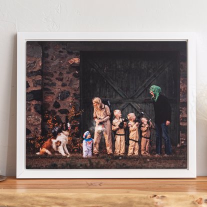 A float frame metal print from Mpix featuring a family dressed up for Halloween as the ghostbusters in front of a giant barn door with a white metal frame. 