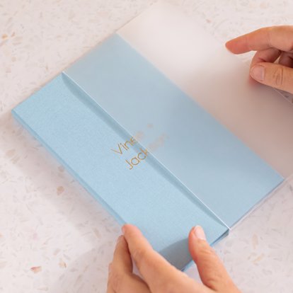 an accordion photo book with a frosted slip cover and blue cloth with personalized debossing