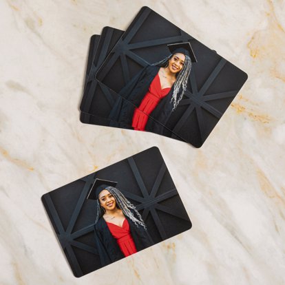 horizontal orientation photo wallet showing graduation photos of a young woman graduate in front of a black barn door with her cap and gown.