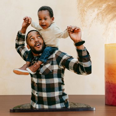 A photo cutout, also known as a statuette, of a father with his young son on hid shoulders.