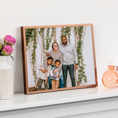 A framed print of a young family displayed on a white mantle.