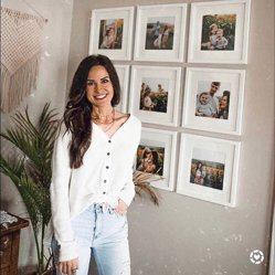 A woman smiling beside a grid of white-framed family photos