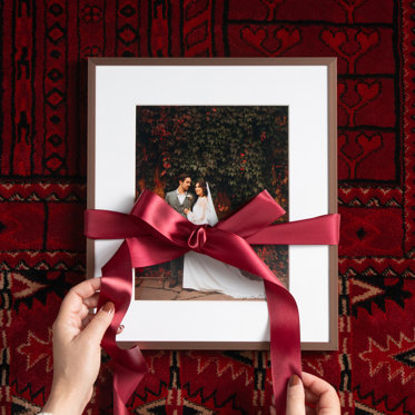 Personalized framed print from Mpix of a wedding photo of a bride and groom with a white mat and thin copper colored metal frame, being wrapped in a red bow.