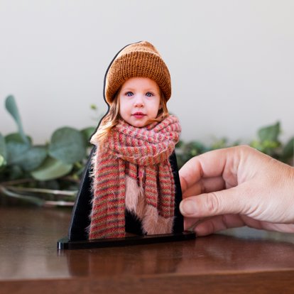 a small statuette of a young girl dressed for the holidays with a big cozy scarf