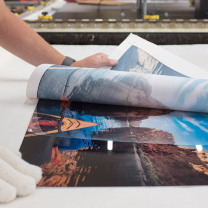 A worked in our lab handcrafts a metal photo print using a heat transfer process before framing.