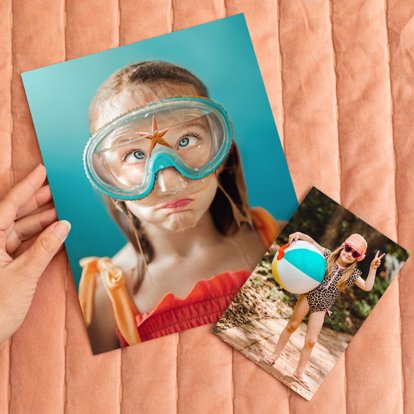 Photo prints showing summer snapshots of a girl with swimming goggles on making a funny face, and a girl posing with her beachball by the pool. 