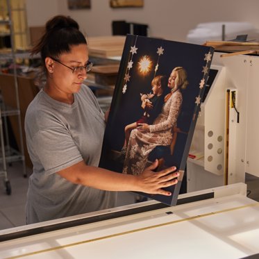 a worker at Mpix inspecting a canvas print for quality