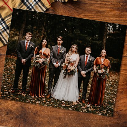 A photo print sitting on a wood table and featuring a wedding image from a fall wedding.