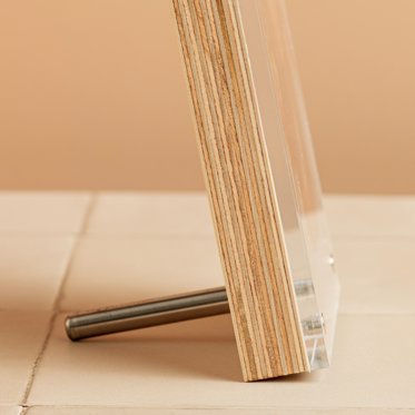 A close up image of the side view of a birch photo block, showing the acrylic piece magnetized to the birch wood block and displayed with a metal dowel to stand.