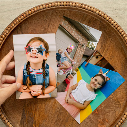 Three colorful 4x6 photo prints laid out on a table each featuring a young girl outside enjoying summer. 