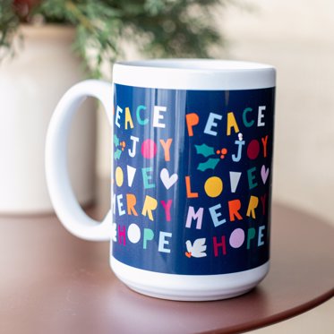 A personalized mug from Mpix featuring a holiday message of peace joy love and merry in colorful handdrawn font on a blue background. 