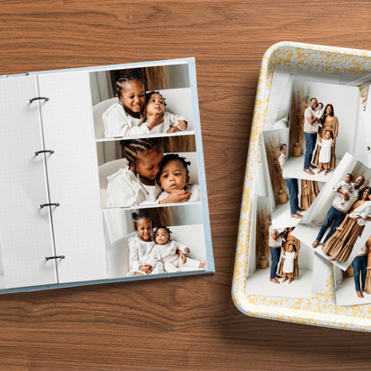 An open slip-in photo album set on a table next to a tray with 4x6 prints. The photos feature shots from a family session with a couple and their two young children against a white background..