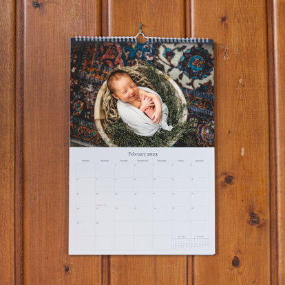 a wall photo calendar with a photo from a newborn session on top of the calendar grid