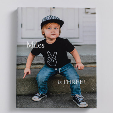 A custom image hardcover book with a matte finish cover featuring an image of a young boy with the text "Miles is three!". 