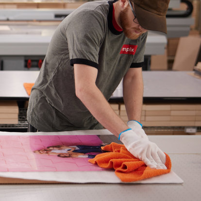 An employee in the Mpix lab uses a microfiber towel to clean their metal print.