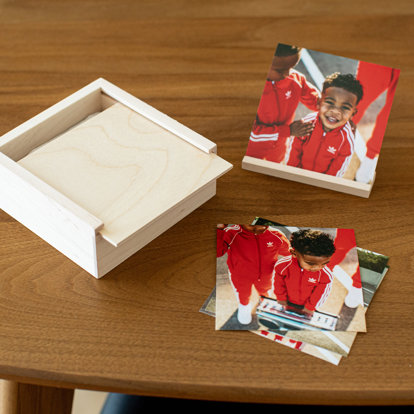 a collection of photo prints sitting outside a wood photo box on a table