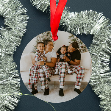 Hands holding a photo ornament with red ribbon for hanging featuring a photo of two brothers outside in a snowy setting.