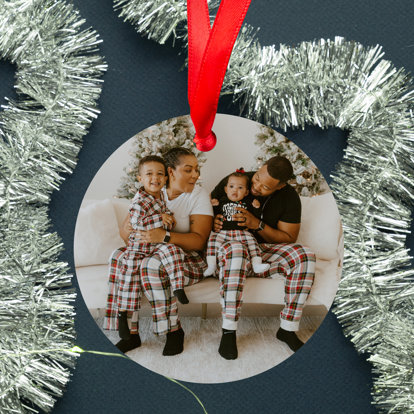 A circular metal ornament featuring a photo of family in Christmas pajamas.