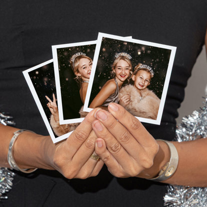 Hands holding three photo prints featuring two sisters dressed up for a New Year's party and wearing 'Happy New Year' headbands.