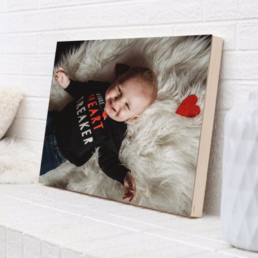 Mpix wood photo print resting on a ledge with a photo of a toddler laying on a furry blanket with a red heart. 