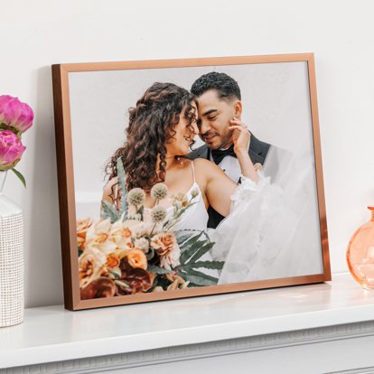 A framed print displayed on a mantle and featuring a wedding photo of a bride and groom.