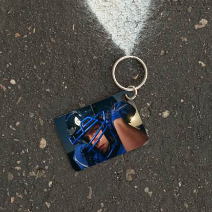 metal keychain with a photo of a football player securing his helmet.