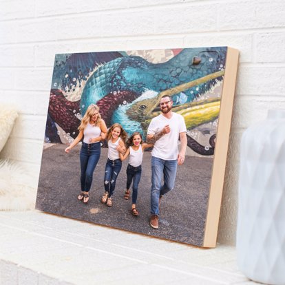 A wood photo print of a family posing in a parking lot with a wall of colorful graffiti behind them.