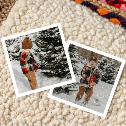 Two 4x4 photo prints with a white border featuring a toddler boy at a snowy tree farm with his toy chainsaw. 