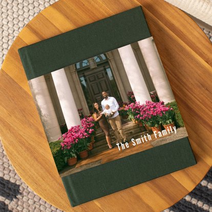 A photo book with a dark green linen cover and skinny dust jacket featuring a young couple with their baby boy standing outside their home. The book is entitled 'The Smith Family'.