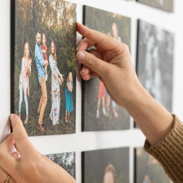 An arrangement of 8x8 photo tiles on a wall featuring pictures of a family. 