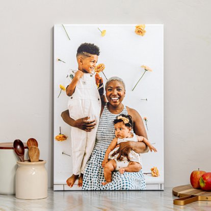 A large canvas print displayed on a kitchen counter featuring a photo of a mom with her son and baby girl. 