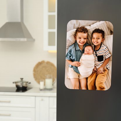 a lovely picture of kids celebrating their newborn sibling printed on a magnet in bright colors and displayed on the fridge