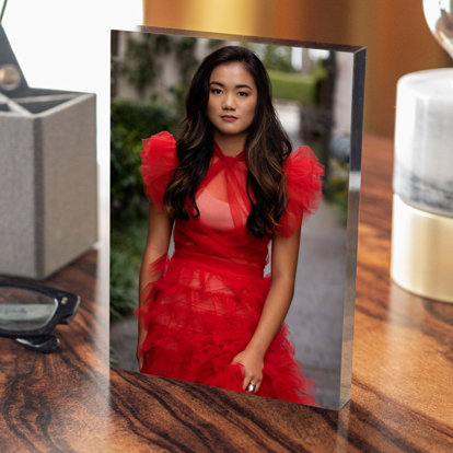 acrylic block print of a girl in a red dress vertically resting on a wooden table