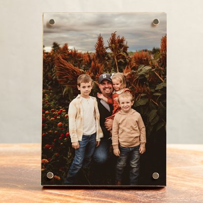 A vertical birch photo block on a table featuring a photo of a father with his three children.