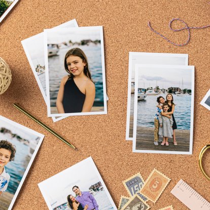 Photos in a Signature Print Set scattered out on a table featuring different images of a young family outside near a marina.