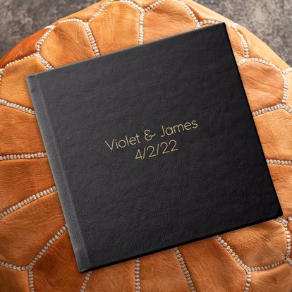 Wedding Photo Album from Mpix with Black Leather Cover and Gold Debossing writing "Violet & James 4/2/22" on the front. 