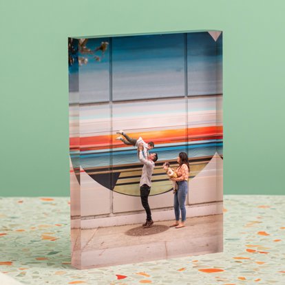 An acrylic photo block standing on a counter and featuring an image of a family in front of a colorful mural.