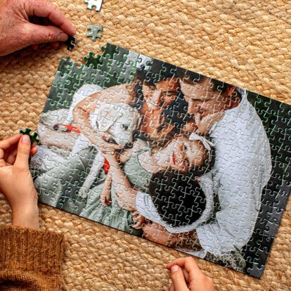 A close-up of hands putting together a photo puzzle from Mpix featuring an image of a family with their pet dog.