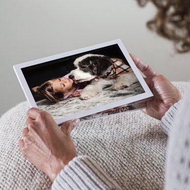 A softcover photo book from Mpix being looked at with a large image cover featuring a girl playing with her dog.