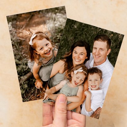 A close up of a hand holding two 4x6 prints featuring images from a family portrait session.