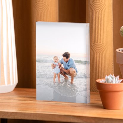 An acrylic photo block from Mpix displayed on a table and featuring an image of a father and young child walking on the beach.